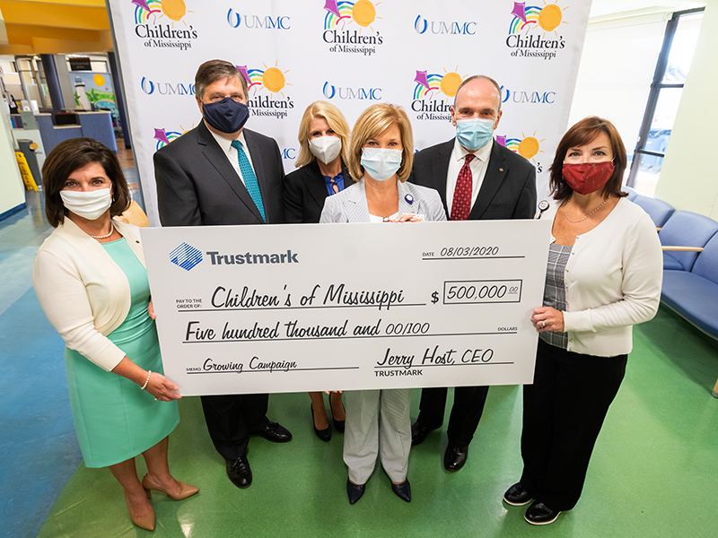 Smiling behind their masks about Trustmark's support of children's health care are, from left, Melanie Morgan, Trustmark senior vice president and director of corporate communications and marketing; Jerry Host, Trustmark chairman and CEO; Meredith Aldridge, Children's of Mississippi director of development; Dr. LouAnn Woodward, UMMC vice chancellor for health affairs; Duane Dewey, Trustmark president and COO; and Dr. Mary Taylor, Suzan B. Thames Chair and professor and chair of pediatrics.  